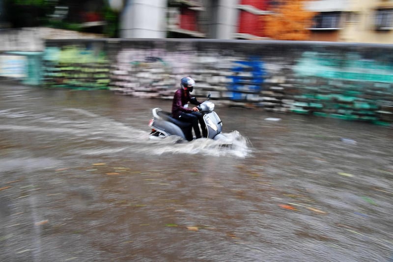A man rides a scooter through a waterlogged street in Mumbai after heavy rainfall from Cyclone Tauktae. AFP