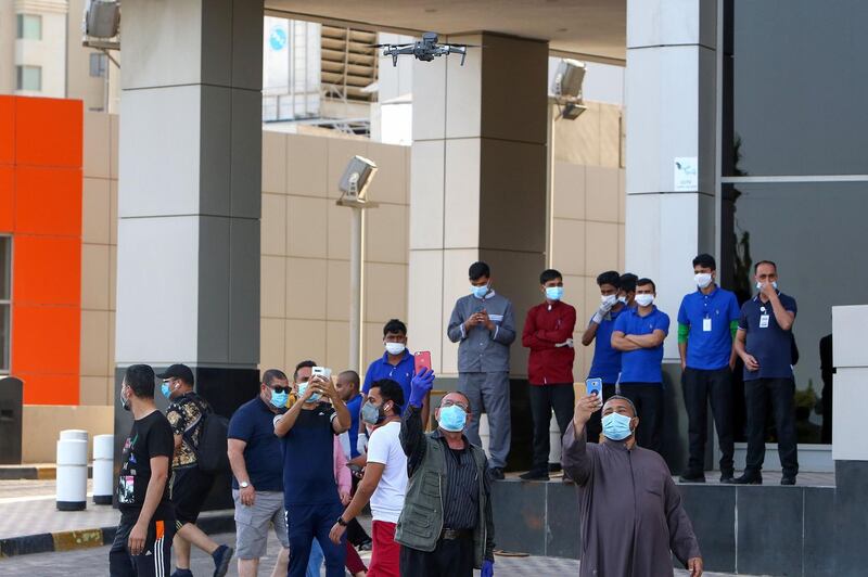 Mask-clad residents take pictures of a surveillance drone in a neighbourhood of Kuwait city on May 12, 2020, as authorities allowed people to exercise for two hours under a nationwide lockdown due to the COVID-19 pandemic. / AFP / YASSER AL-ZAYYAT
