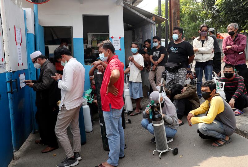 People wait for their turn to refill their oxygen tanks at a recharging station in Jakarta, Indonesia.