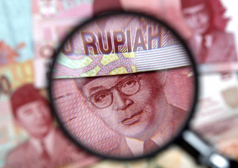 One hundred thousand rupiah notes are seen through a magnifying glass in this photo illustration taken in Singapore. Banks in Singapore are stubbornly against adopting domestically set reference rates for derivative contracts in the Indonesia rupiah, despite preparing to drop their own rate fixing for the Malaysian ringgit and Vietnamese dong. Reuters, file