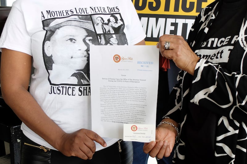 Deborah Watts and Priscilla Sterling, cousins of Emmett Till, show a document used by Mississippi Attorney General Office representative Wayne Lynch to indicate receipt of a poster and accompanying thumb drive that reportedly holds almost 300,000 signatures on a petition seeking a renewed investigation into Till's 1955 lynching. AP