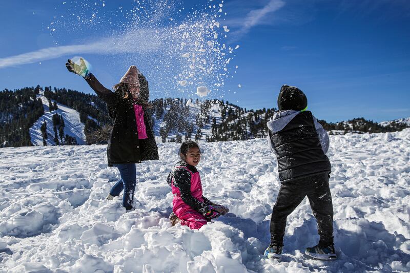 Jane Cabrillos, left, her 7-year-old daughter Janelle Cabrillos and nephew Jedrick Bautista, 5, play in the snow along Table Mountain Road.