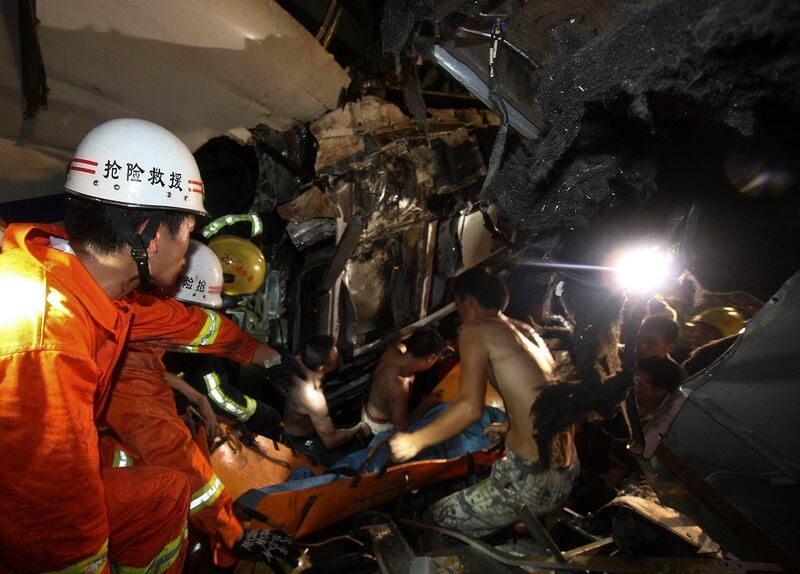 Emergency workers and civilians carry the body of a passenger killed in a train crash in Wenzhou in east China's Zhejiang province, Saturday, July 23, 2011. A Chinese bullet train lost power after being struck by lightning and was hit from behind by another train, knocking two of its carriages off a bridge, killing at least 16 people and injuring 89, state media reported. (AP Photo) CHINA OUT *** Local Caption ***  China Train Crash.JPEG-05574.jpg