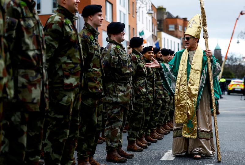 Irish Army soldiers stand guard as a participant dressed as St  Patrick walks in front of them during the annual St Patrick's Day parade in Dublin. Reuters
