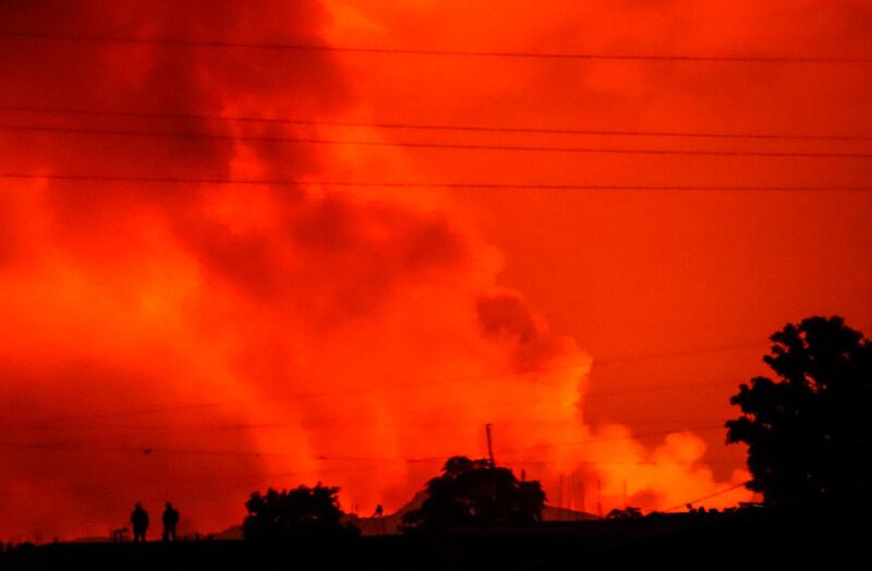 Two figures are silhouetted against a night sky turned red by the eruption of Mount Nyiragongo. AP