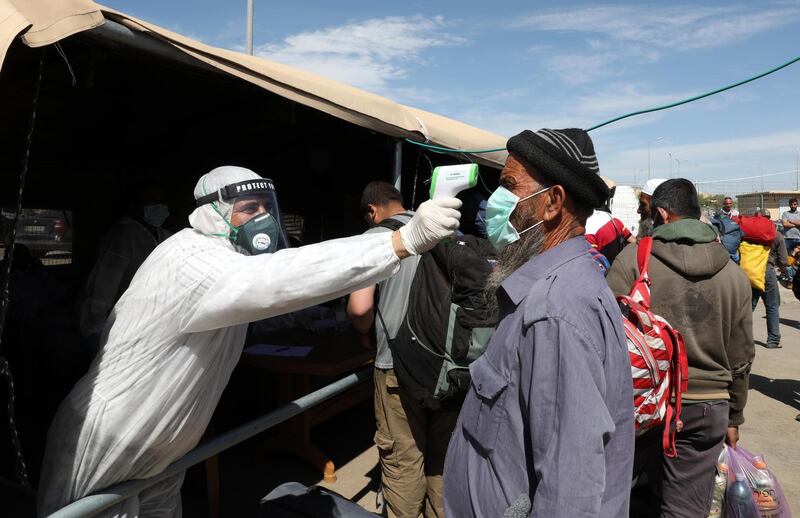 epa08380077 Medical staff of the Palestinian health ministry checks the temperature of workers crossing the checkpoint of Mitar, near the West Bank town of Hebron, 23 April 2020. The instructions of the National Authority Ministry of Health forbid gatherings and movement between cities to prevent the spread of the SARS-CoV-2 coronavirus which causes the COVID-19 disease.  EPA/ABED AL HASHLAMOUN