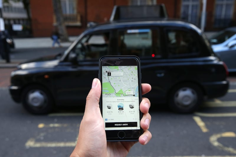 A woman poses holding a smartphone showing the App for ride-sharing cab service Uber in London on September 22, 2017.
London transport authorities announced today they would not renew Uber's licence to operate in the city when it expires on September 30 for safety reasons, although it has three weeks to appeal. / AFP PHOTO / Daniel LEAL-OLIVAS