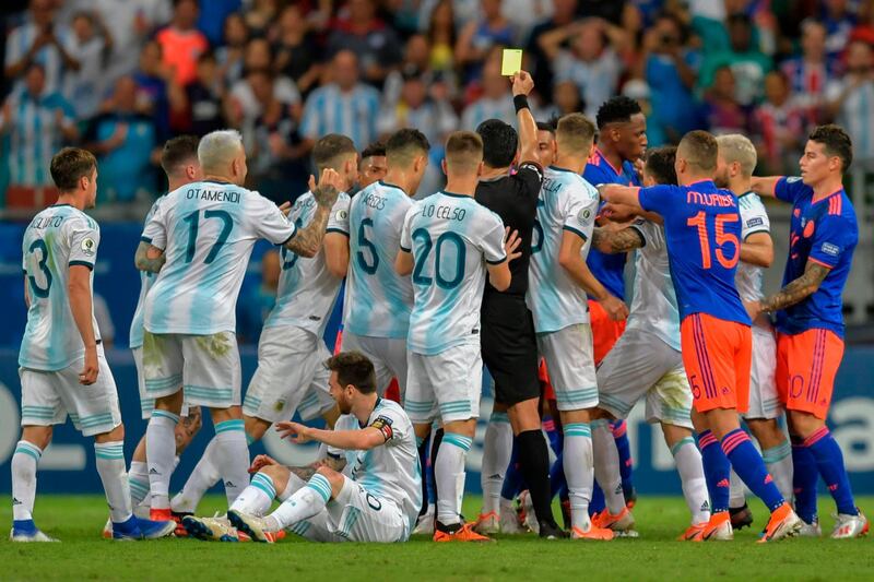 Peruvian referee Diego Haro awards a yellow card to Colombia's Juan Cuadrado after fouling Argentina's Lionel Messi. AFP