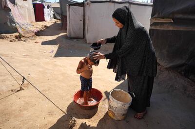 A Palestinian woman bathes a child at a camp for displaced people, in Deir Al Balah, central Gaza Strip. AFP
