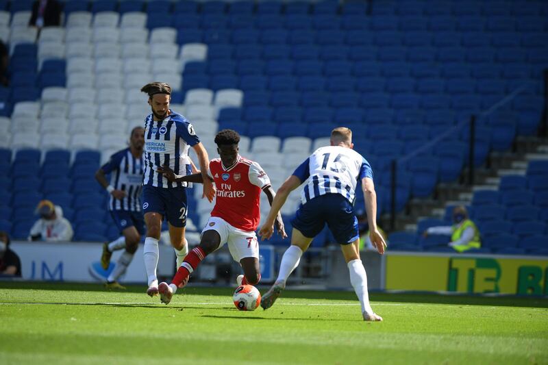 Bukayo Saka of Arsenal is challenged by Davy Propper and Adam Webster of Brighton & Hove Albion. Getty