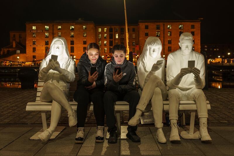Teenagers pose with their phones next to the light installation 'Absorbed By Light', before the launch of the annual River of Light Trail in Liverpool, England. Getty Images
