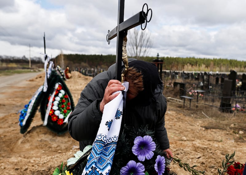 Galina Bondar, 63, who said her son, Olexander Bondar, 32, a territorial defence member, was killed by Russian troops, kisses the plaque bearing his name at his grave in Bucha. Reuters