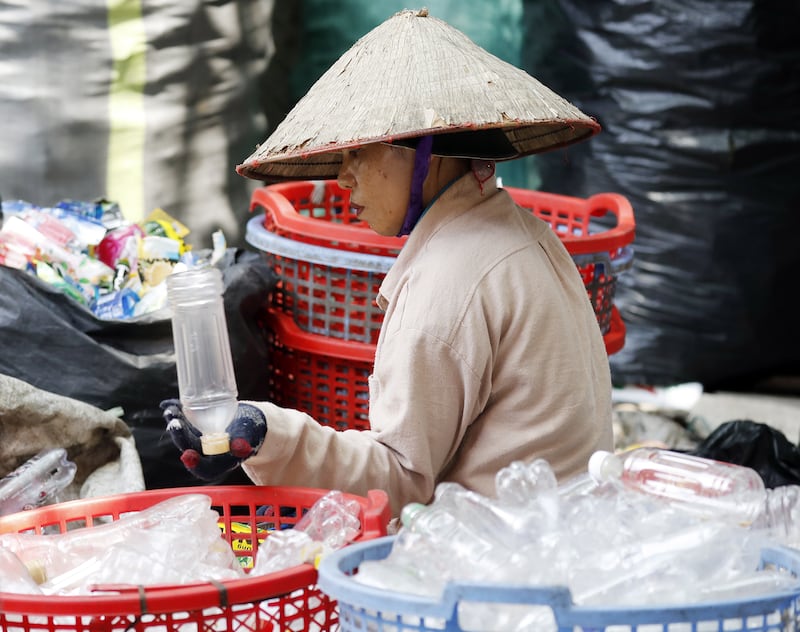 A woman removes labels and classifies plastic waste at a plastic recycling craft village in Hanoi, Vietnam.  EPA