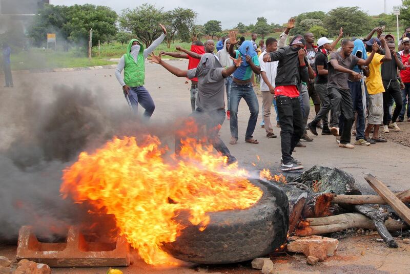 FILE PHOTO: Protesters stand behind a burning barricade during protests on a road leading to Harare, Zimbabwe, January 15, 2019. REUTERS/Philimon Bulawayo/File Photo