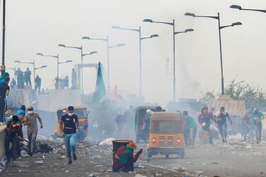 Iraqi demonstrators run from tear gas at Al Jumariyah Bridge during a protest against corruption, a lack of jobs and poor services. Reuters 