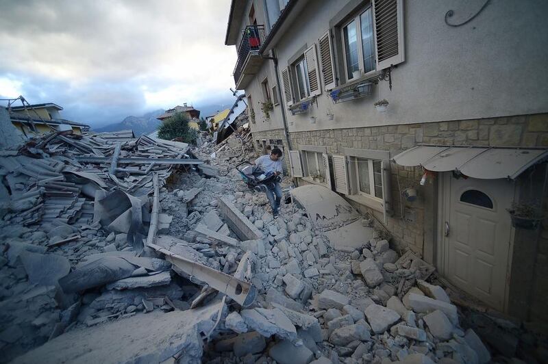 A resident carries a pram among damaged buildings after a strong heartquake hit Italy. The magnitude 6.2 quake struck at 3:36 a.m. and was felt across a broad swath of central Italy, including Rome, where residents felt a long swaying followed by aftershocks. Filippo Monteforte / AFP