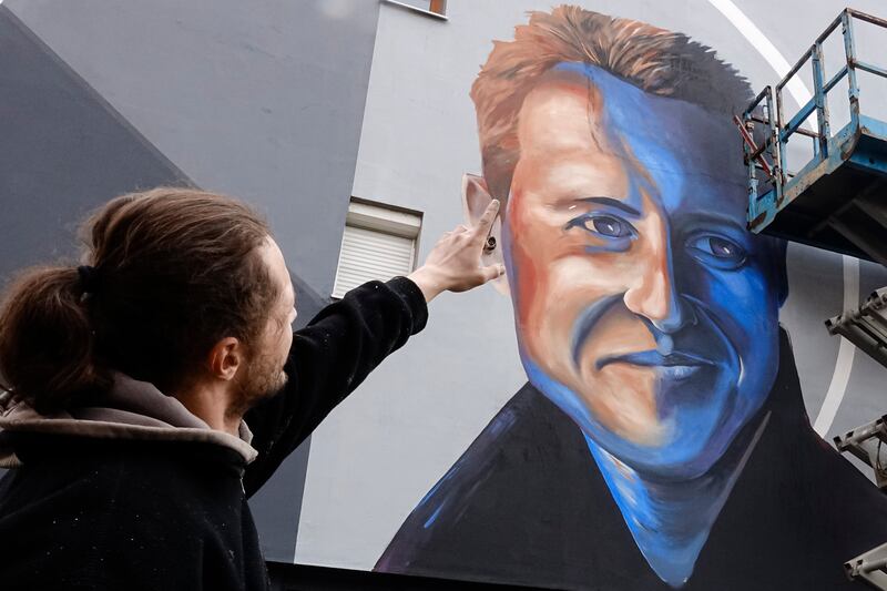 Bosnian artist Benjamin Cengic speaks to colleagues applying finishing touches to his mural of Michael Schumacher on a building which was rebuilt with the F1 star's support in Sarajevo, Bosnia. AP
