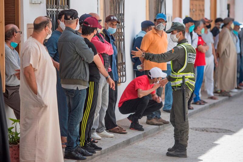 A member of Morocco interior ministry's auxiliary forces assists taxi drivers as they queue for coronavirus testing in the capital Rabat. AFP