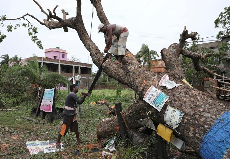 Men cut branches of an uprooted tree in the aftermath of Cyclone Amphan, in South 24 Parganas district in the eastern state of West Bengal, India. REUTERS