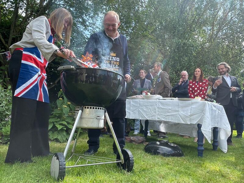 Mr Davey grills burgers in a garden, during campaigning in Wiltshire. PA