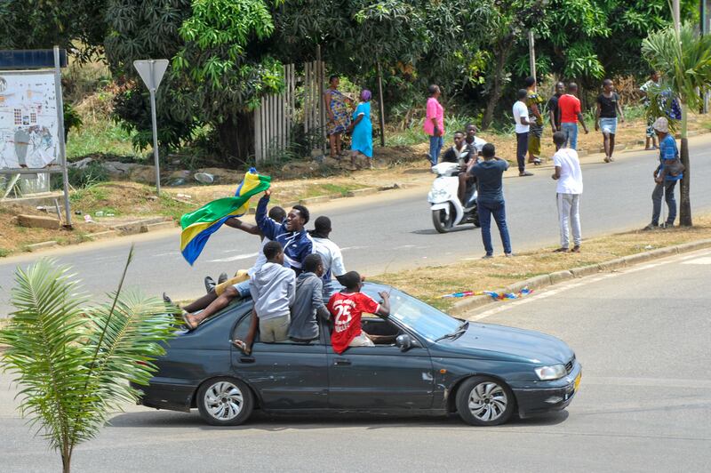 People wave Gabon national flags in the streets of Akanda. EPA
