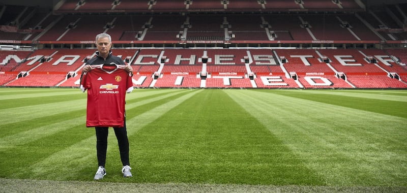 Manchester United's new Portuguese manager Jose Mourinho poses with a football shirt on the pitch during a photocall at Old Trafford stadium in Manchester, northern England, on July 5, 2016.
Jose Mourinho officially started work as Manchester United manager at the club's Carrington training base yesterday. The 53-year-old was appointed as United boss in May after the sacking of Dutchman Louis van Gaal. / AFP PHOTO / OLI SCARFF