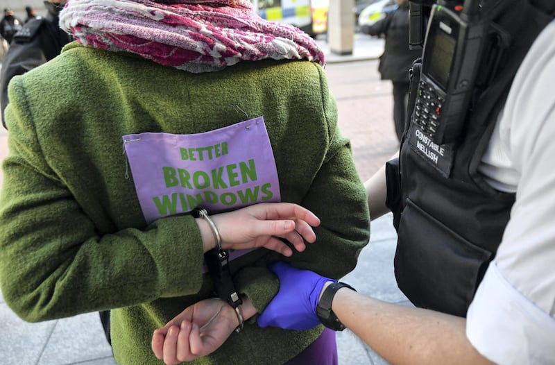 A police officer detains an activist from the Extinction Rebellion, a global environmental movement, outside the Barclays offices in Canary Wharf, London, Britain, April 7, 2021. REUTERS/Toby Melville