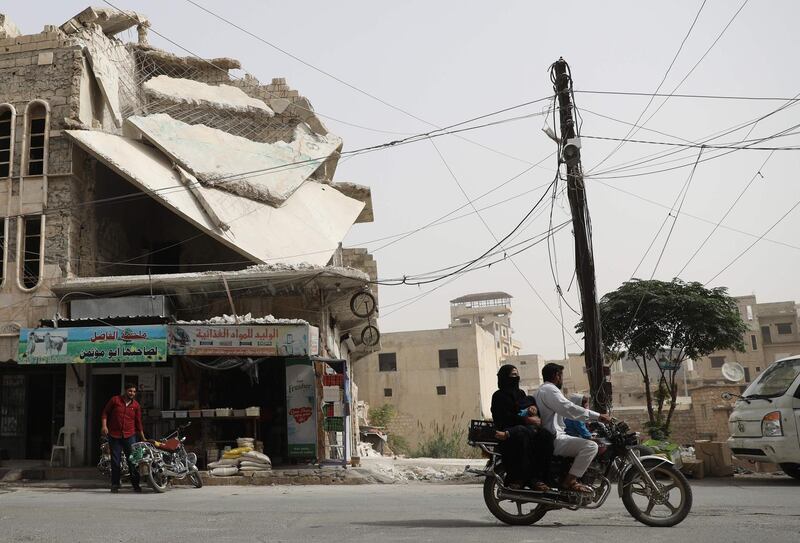 A man drives his motorcycle past a damaged building in the town of Binnish, in Syria's rebel-held northern Idlib province on October 15, 2018.  Jihadists in Syria's Idlib failed to meet a deadline to leave a planned buffer zone ringing the country's last rebel bastion, casting fresh doubt over a deal to avert bloodshed.  / AFP / OMAR HAJ KADOUR
