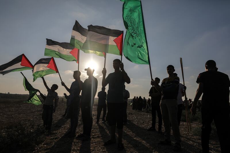 Palestinian protesters hold flags during clashes with Israeli troops on the eastern borders of Gaza Strip on Monday. EPA