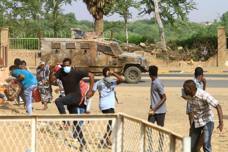 Sudanese anti-coup demonstrators duck for cover as a police vehicle fires tear gas towards them in the capital's twin city of Omdurman on Sunday.  AFP