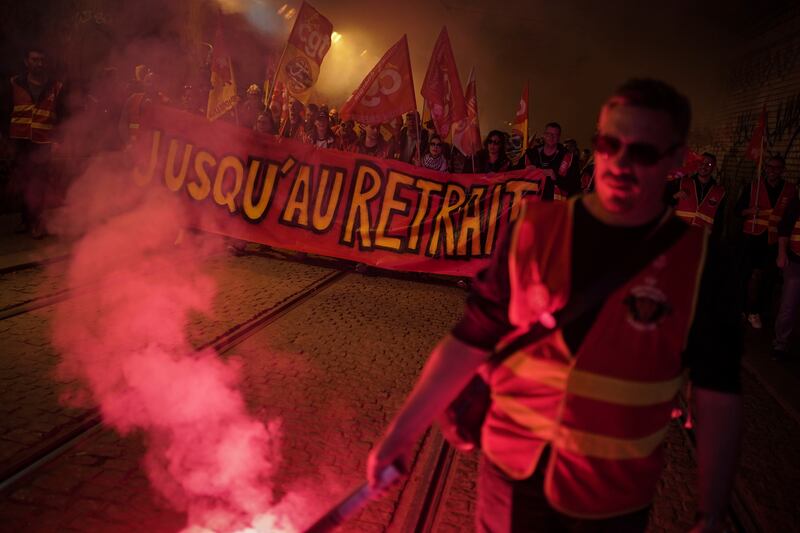 Railway workers hold a banner reading 'Until withdrawal' at a demonstration in Lyon. AP