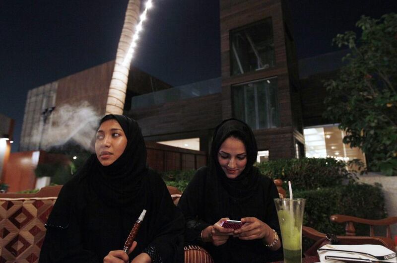 In this file photo, a Saudi woman smokes tobacco from a waterpipe while sitting in a coffee shop with a friend in Jeddah, Saudi Arabia. The number of single Saudi women in the kingdom is on the rise, a trend scoffed at by conservatives. Hassan Ammar/AP Photo