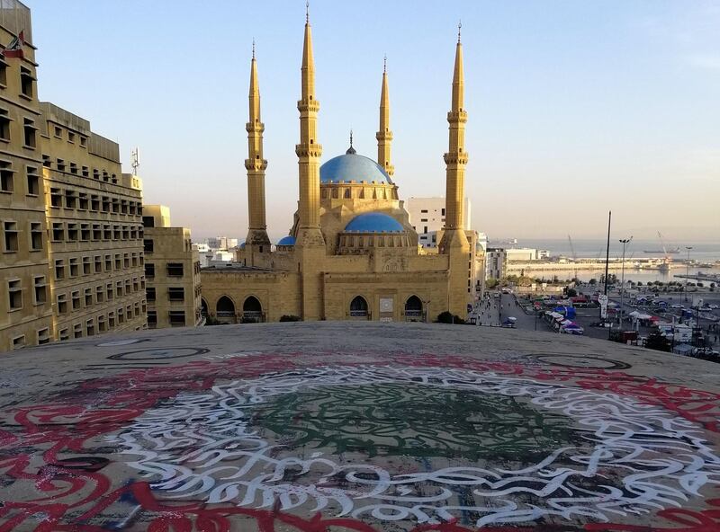 A picture taken on November 5, 2019, shows graffiti on top of the Dome City Center known as "The Egg", next to the Mohammed al-Amin mosque, in downtown Beirut during sunrise. Demonstrators in Lebanon blocked key roads and prevented some public institutions from opening after mass rallies showed political promises had failed to extinguish the unprecedented protest movement. / AFP / Jean Marc MOJON
