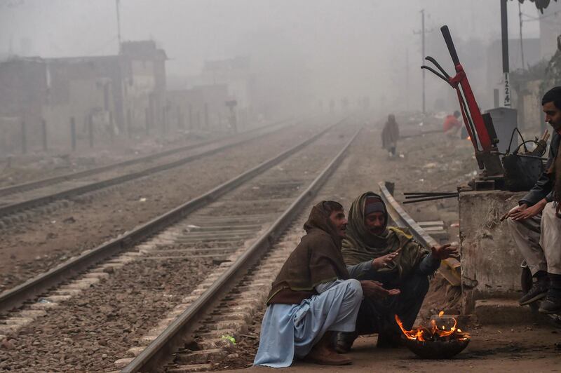 Railway workers warm themselves around a fire during smog and fog conditions, in Lahore, Pakistan. AFP