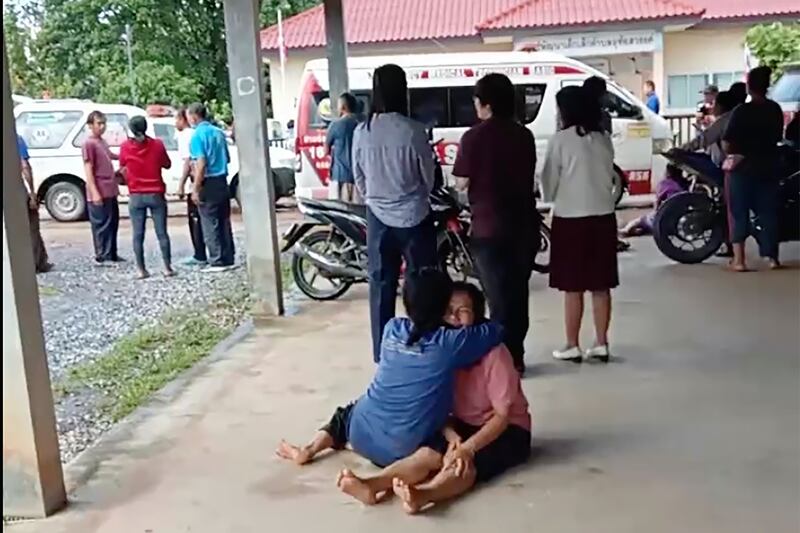 In this image taken from video, a distraught woman is comforted outside the site of an attack at a daycare centre in the town of Nongbua Lamphu, north-eastern Thailand. AP