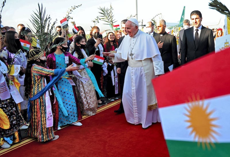 Pope Francis greets Iraqis dressed in traditional outfits upon his arrival at Erbil airport on March 7, 2021, in the capital of the northern Iraqi Kurdish autonomous region. Pope Francis, on his historic Iraq tour, visits today Christian communities that endured the brutality of the Islamic State group until the jihadists' "caliphate" was defeated three years ago. / AFP / Safin HAMED
