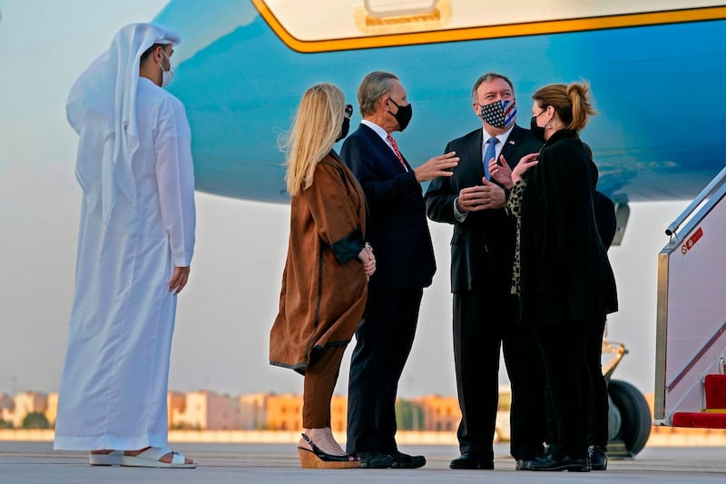 US Secretary of State Mike Pompeo (2nd-R) and his wife Susan (R) speak with US Ambassador to the United Arab Emirates John Rakolta and his wife Terry after stepping off a plane at al-Bateen Executive Airport in Abu Dhabi on November 20, 2020.  / AFP / POOL / Patrick Semansky
