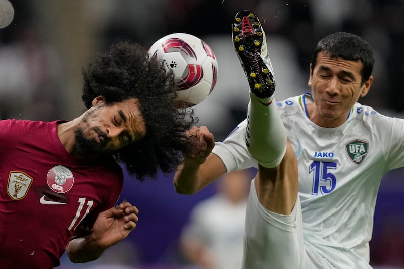 Qatar's Akram Afif, left, and Uzbekistan's Eshmurodov Umarbek fight for the ball. AP