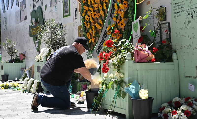 A man lays a wreath at the Grenfell Tower Memorial Wall. EPA