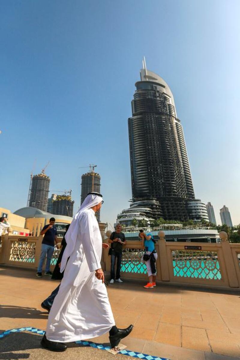 People walk by the damaged hotel in Downtown Dubai. Shot from Souk Al Bahar footbridge.