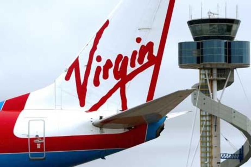 A Virgin Airline plane taxiing past the air traffic control tower after landing at Sydney Airport.