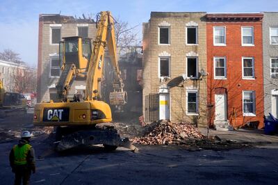 An excavator is used to pull debris off a building during efforts to retrieve the body of a deceased firefighter caught in the building's collapse. AP