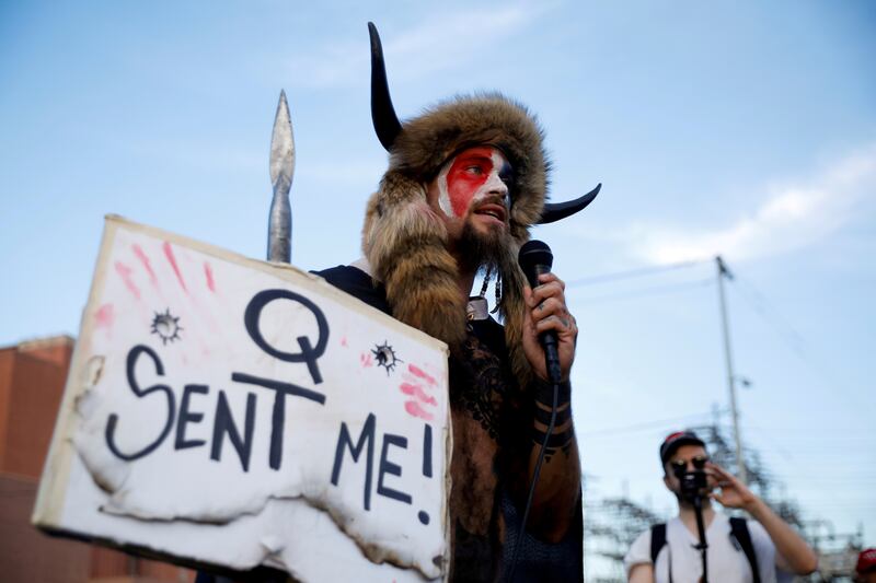 Rioter Jacob Chansley holds a sign referencing QAnon as supporters of Mr Trump gather to protest the early results of the 2020 presidential election. Reuters