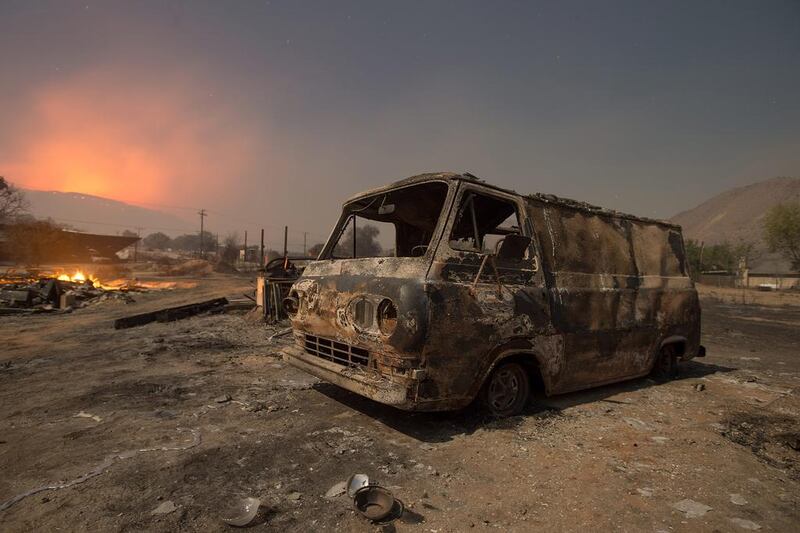 Seen in a long exposure night-time photograph, a burnt van while a wildfire glows on the horizon in Phelan, California. Noah Berger / AP Photo