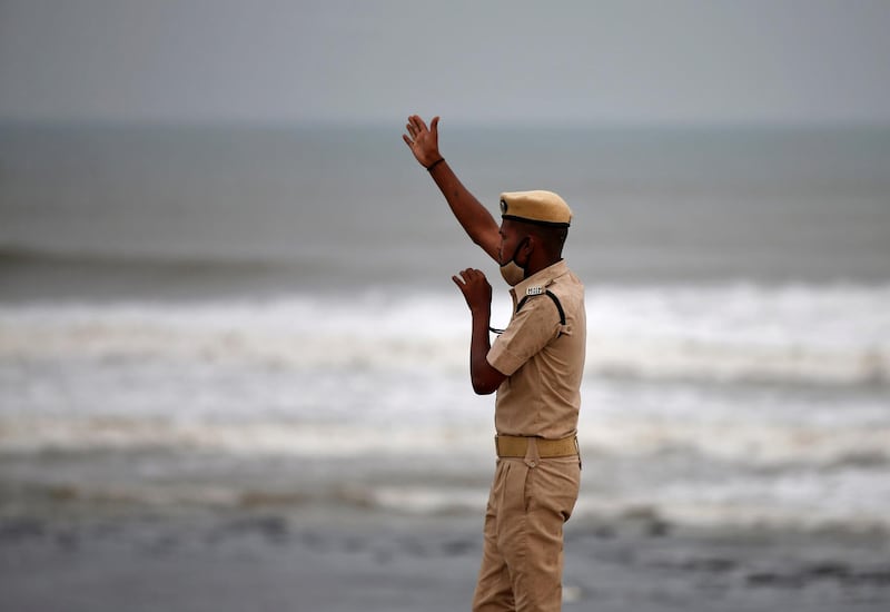 A police officer in Veraval, Gujarat, directs people to leave as waves approach the shore before the arrival of Cyclone Tauktae. Reuters