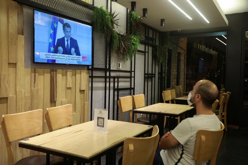 An employee watches a news conference of French President Emmanuel Macron on the political situation in Lebanon, inside an empty restaurant in Beirut. Reuters