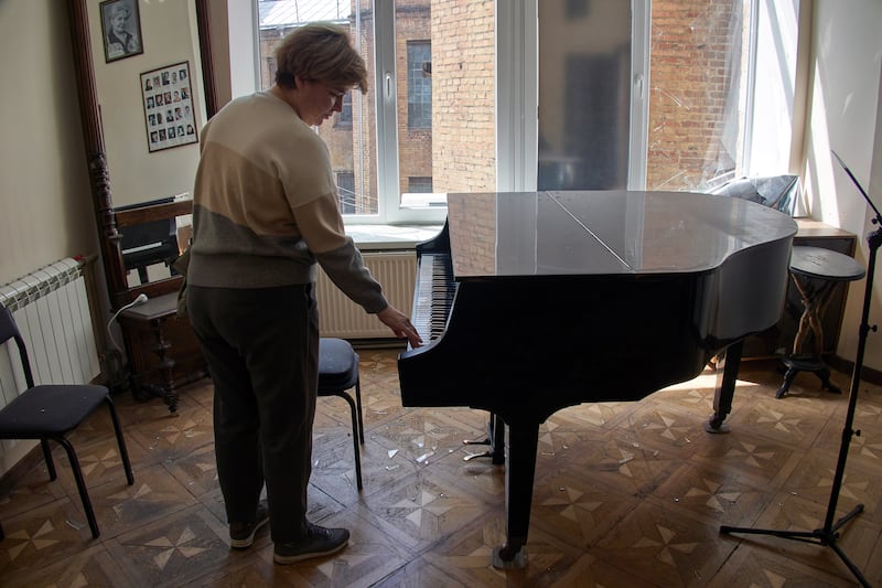 A woman touches a piano as she inspects the damage in a classroom after shelling at Kharkiv National Kotlyarevsky University of Arts. EPA