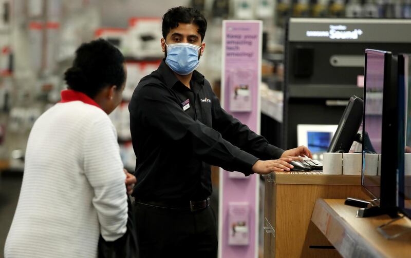 An employee wearing a protective face mask talks to a customer at the Staples Corner Megastore for Carphone Warehouse and Curry's PC World, as shops re-open following the outbreak of the coronavirus disease, in Brent Cross, London, Britain, June 15, 2020. REUTERS