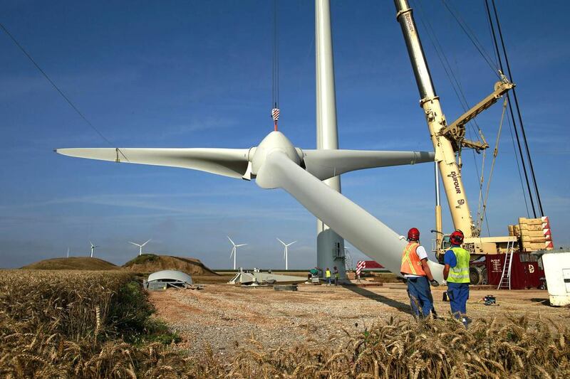 Workers lift a rotor hub on the tower part of an E-70 wind turbine during its installation at a wind farm in Meneslies. France will mobilise about €10 billion  for a package of tax breaks, low-cost loans, and bonuses to boost investment in renewable energy. Benoit Tessier / Reuters