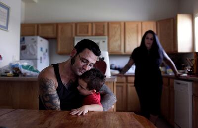 In this Monday, Aug. 1, 2011 photo, Bryon Widner hugs his 4-year-old son, Tyrson, at their home as his wife Julie watches. After getting married in 2006, the couple, former pillars of the white power movement (she as a member of the National Alliance, he a founder of the Vinlanders gang of skinheads) had worked hard to put their racist past behind them. They had settled down and had a baby; her younger children had embraced him as a father. (AP Photo/Jae C. Hong)